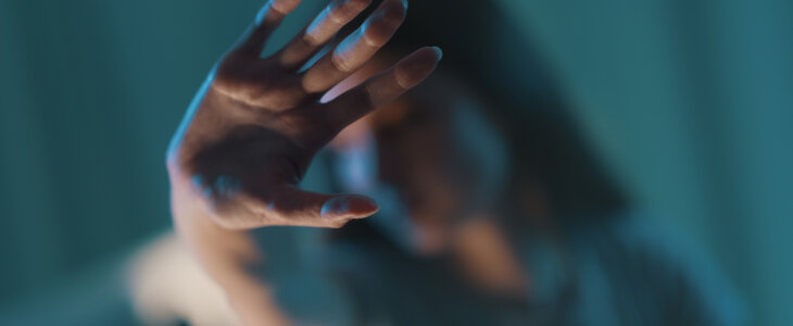 A woman puts her hand up to block her face