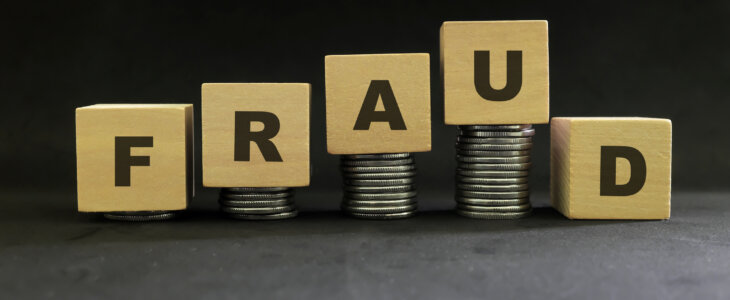 Investment scam, fraud and Ponzi scheme concept. Stack of coins on wooden blocks with word ponzi in dark black background.